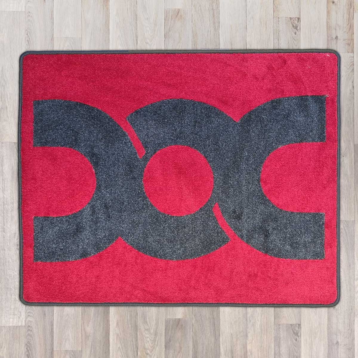 Large rectangular floor rug with Dubbed Out Community logo on shown in red carpet with grey carpet logo