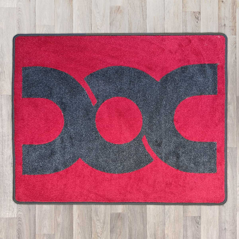 Large rectangular floor rug with Dubbed Out Community logo on shown in red carpet with grey carpet logo