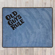 Large rectangular floor rug with Old Guys Rule logo shown in grey carpet with black carpet logo