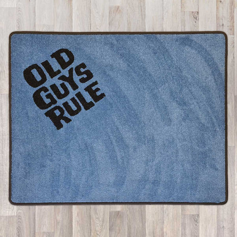 Large rectangular floor rug with Old Guys Rule logo shown in grey carpet with black carpet logo