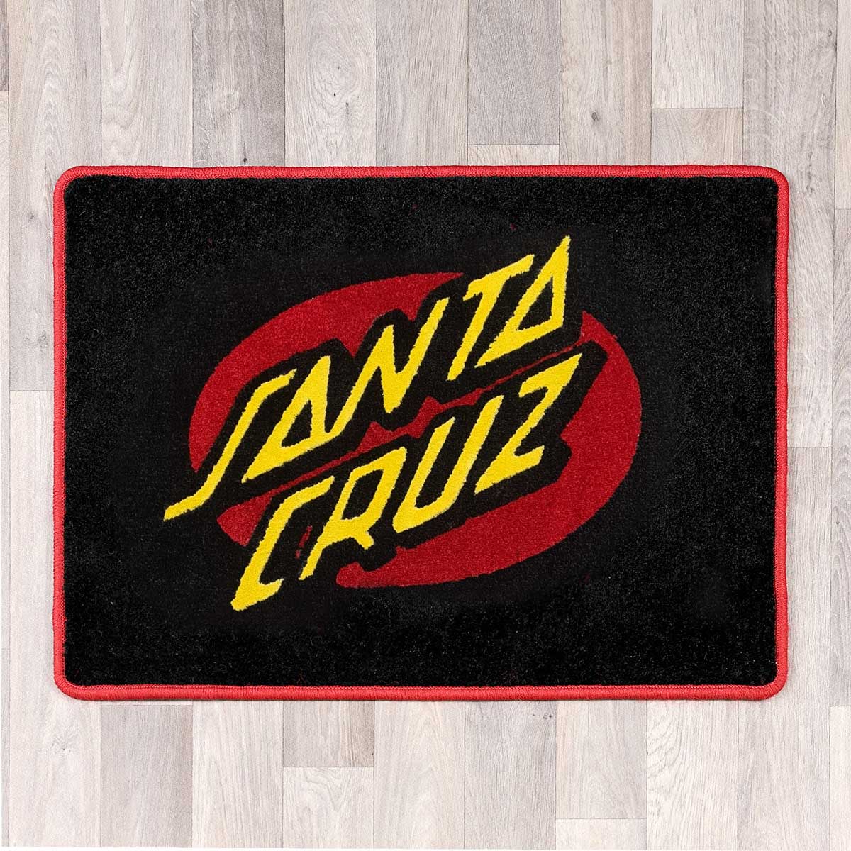 Large rectangular floor rug with Santa Cruz logo shown in black carpet with yellow carpet logo