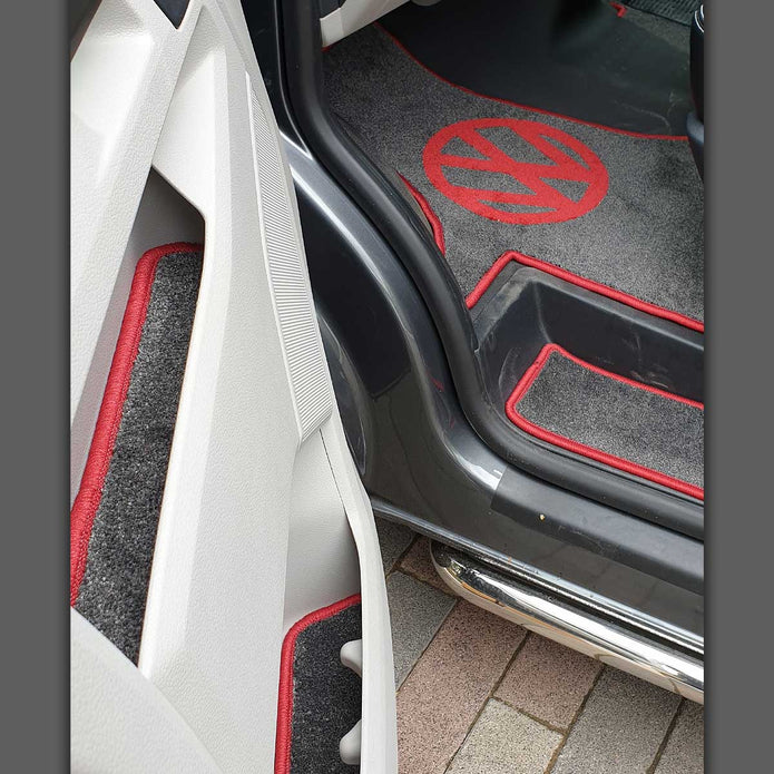 Image of T6 cab, steps, and door pocket liners inside a T6 van cab. Mats shown in grey carpet with red binding.
